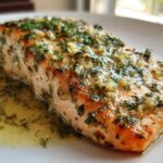 Close-up of a perfectly cooked fillet of Garlic Butter Salmon topped with minced garlic and fresh dill.