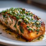 Close-up of a perfectly cooked fillet of Garlic Butter Salmon with Lemon Herb Sauce, glistening with butter and herbs.