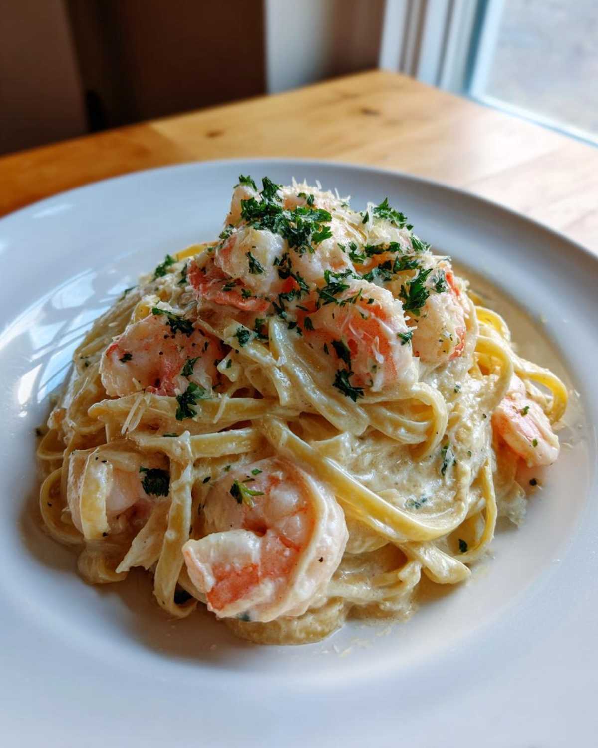 A close-up of rich Garlic Butter Shrimp Alfredo Pasta tossed in a creamy sauce and topped with parsley.