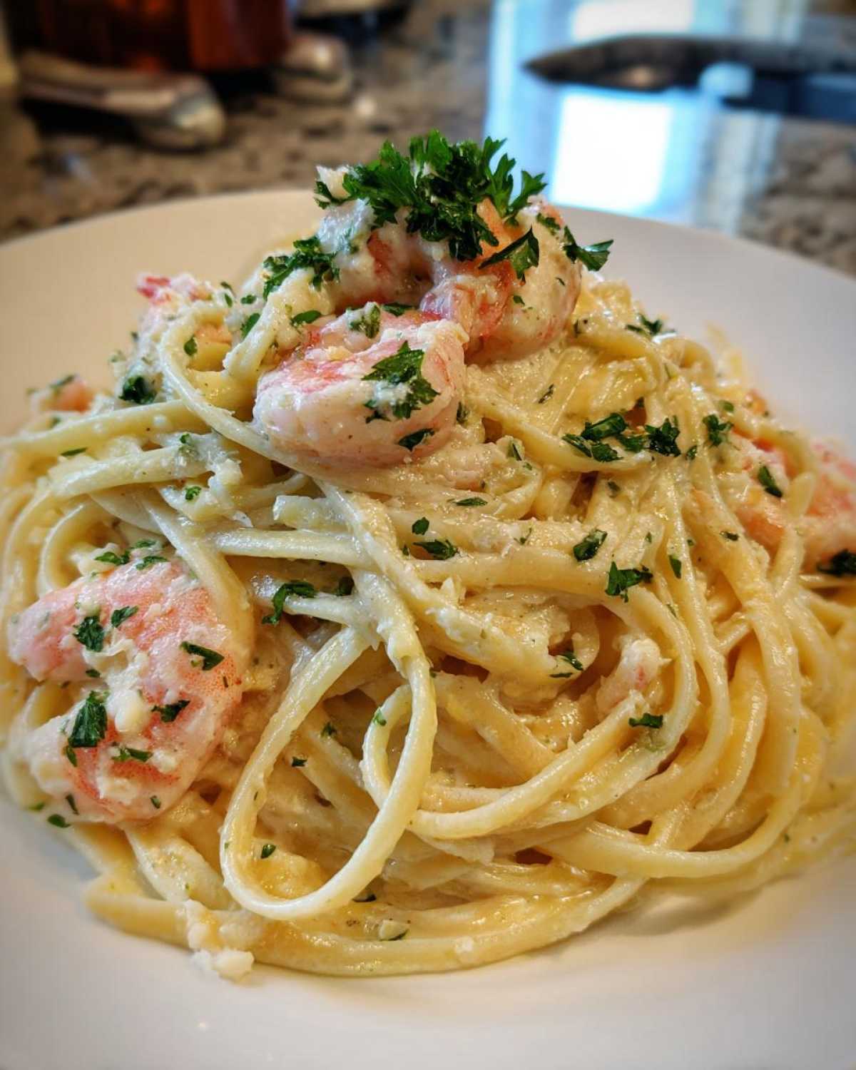 A close-up of a plate of Garlic Butter Shrimp Pasta with Cream Sauce, topped with fresh parsley.