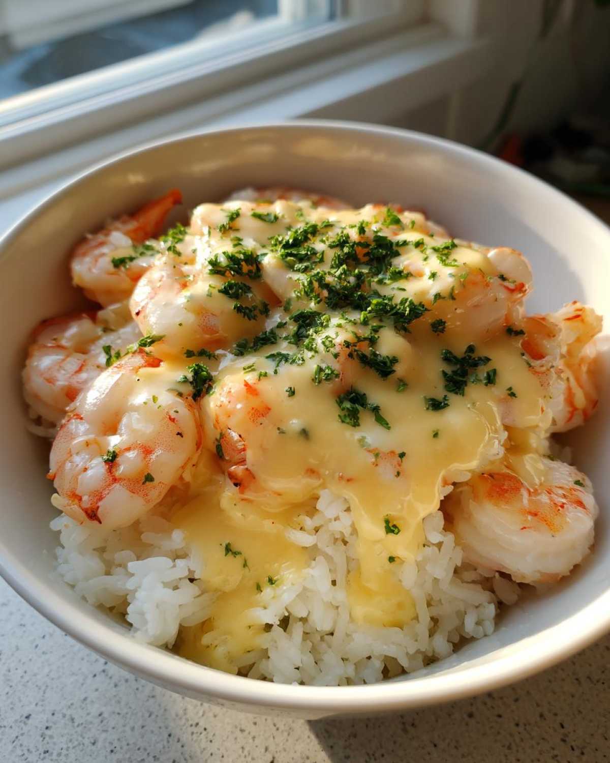 Close-up of a Garlic Butter Shrimp Rice Bowl topped with rich garlic sauce and chopped parsley.
