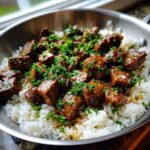 Close-up of Garlic Butter Steak and Rice Skillet Dinner, featuring cubed steak in sauce over white rice, topped with fresh parsley.