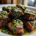 Close-up of seared Garlic Butter Steak Bites generously topped with a vibrant green herb sauce.