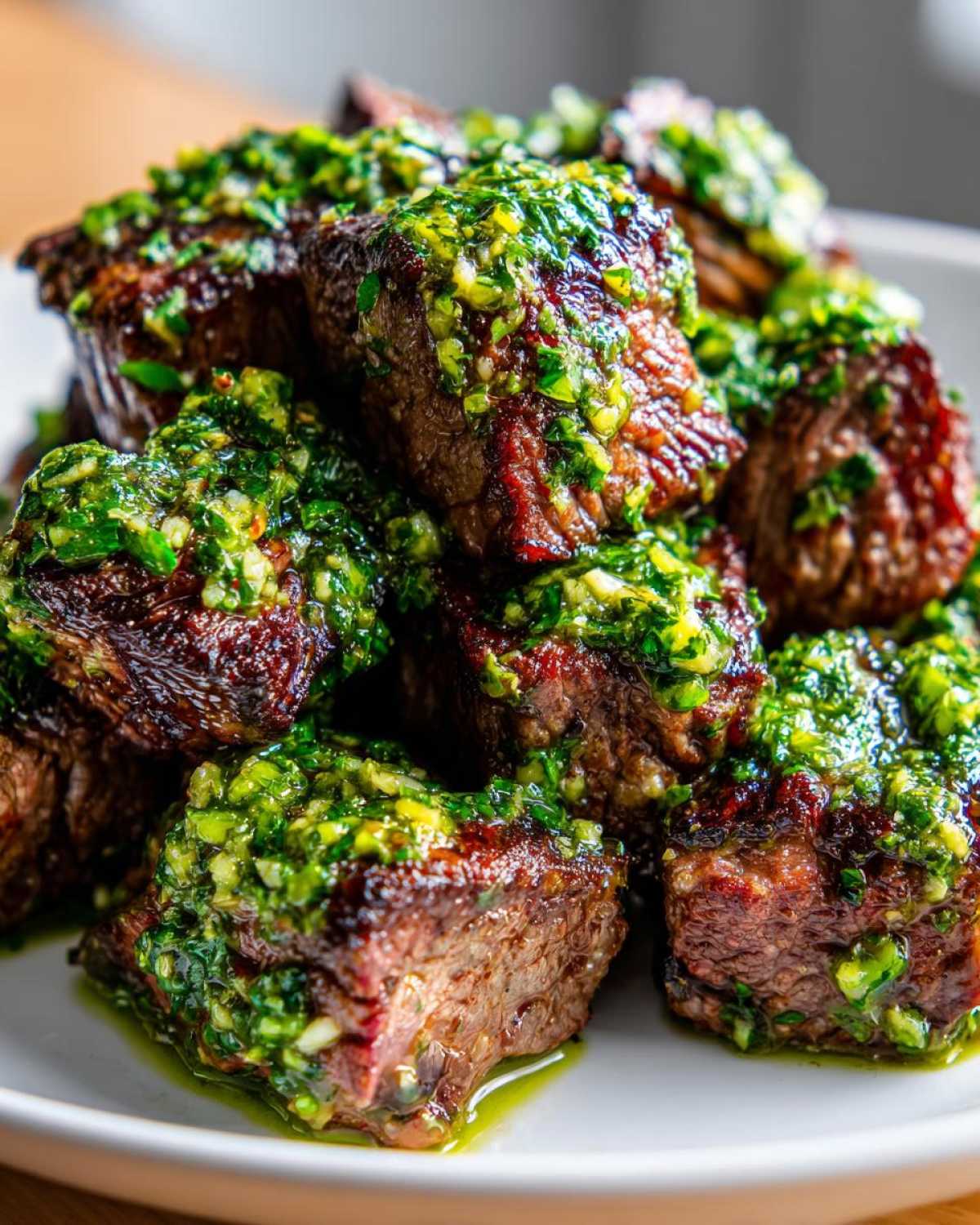 Close-up of perfectly seared Garlic Butter Steak Bites generously topped with a vibrant green herb sauce.