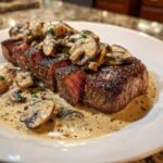 Perfectly cooked Garlic Butter Steak, sliced to show medium-rare center, topped with creamy mushroom sauce.