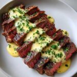 Perfectly cooked, sliced steak drizzled with creamy sauce and fresh herbs, showcasing Garlic Butter Steak with Creamy Sauce.