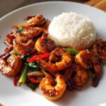 A plate featuring glossy Honey Garlic Shrimp Skillet with Rice, garnished with sesame seeds and vegetables.