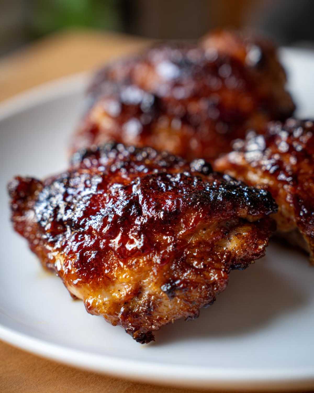 Close-up of perfectly cooked Sticky BBQ Chicken Thighs with a dark, glossy, and crispy caramelized glaze.