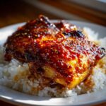 Two glazed Sticky Sweet Chili Chicken Thighs served over a bed of fluffy white rice.