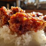 Close-up of glazed Sticky Sweet Chili Chicken Thighs resting on a bed of fluffy white rice.