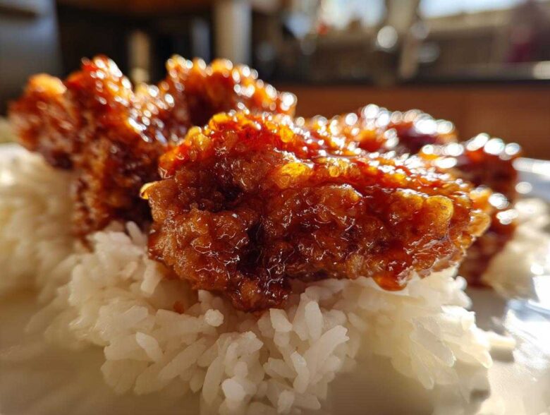 Close-up of glazed Sticky Sweet Chili Chicken Thighs resting on a bed of fluffy white rice.