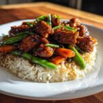 A serving of Sticky Teriyaki Chicken Bowl with rice, glazed chicken pieces, carrots, and green beans.